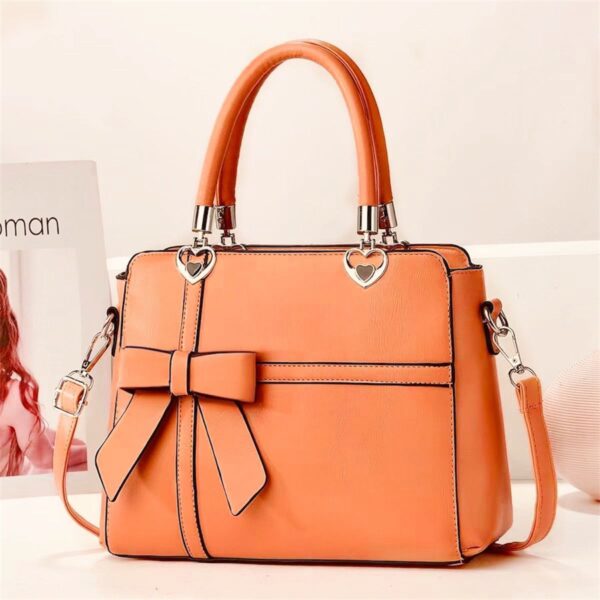 Elegant Bow-adorned Satchel Handbag With Heart Charm Handles And Removable Shoulder Strap